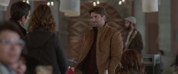 Movie still from “All the Places” (2023), directed by Pitipol Ybarra – A man in a brown jacket is standing next to a woman in a brown jacket; Medium shot, Over the shoulder angle