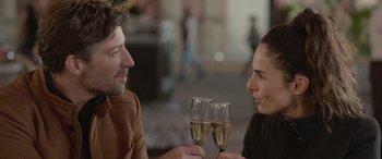 Movie still from “All the Places” (2023), directed by Pitipol Ybarra – A man and a woman are holding wine glasses; Close Up shot, Over the shoulder angle