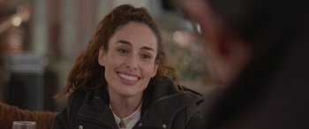 Movie still from “All the Places” (2023), directed by Pitipol Ybarra – A woman smiling for the camera while wearing a jacket; Close Up shot, Over the shoulder angle