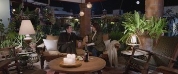 Movie still from “All the Places” (2023), directed by Pitipol Ybarra – A man and a woman are sitting on a couch; Wide shot, High angle