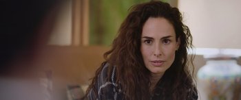 Movie still from “All the Places” (2023), directed by Pitipol Ybarra – A person sitting on a couch; Close Up shot, Over the shoulder angle