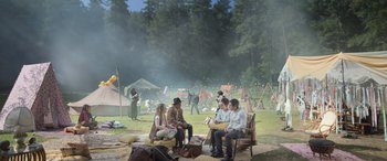 Movie still from “All the Places” (2023), directed by Pitipol Ybarra – A group of people sitting on a bench in a field; Wide shot, High angle