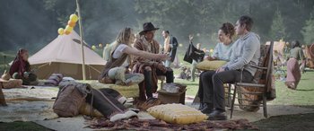 Movie still from “All the Places” (2023), directed by Pitipol Ybarra – A group of people sitting on a blanket in a park; Wide shot, Over the shoulder angle
