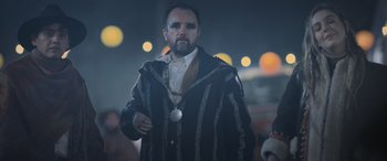 Movie still from “All the Places” (2023), directed by Pitipol Ybarra – A man with a beard wearing a black and white striped coat; Close Up shot, Over the shoulder angle