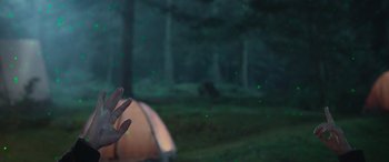 Movie still from “All the Places” (2023), directed by Pitipol Ybarra – A person standing in front of a tent in the woods; Wide shot, Low angle