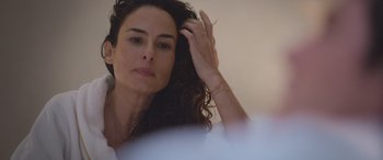 Movie still from “All the Places” (2023), directed by Pitipol Ybarra – A beautiful woman with long dark curly hair looking into a mirror; Close Up shot, Over the shoulder angle