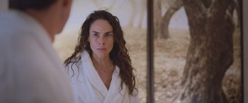 Movie still from “All the Places” (2023), directed by Pitipol Ybarra – A woman in a white bathrobe stands in front of a mirror; Close Up shot, Low angle