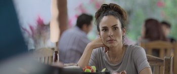 Movie still from “All the Places” (2023), directed by Pitipol Ybarra – A woman sitting in front of a plate of food; Close Up shot, Over the shoulder angle