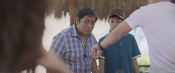 Movie still from “All the Places” (2023), directed by Pitipol Ybarra – A man in a plaid shirt is looking at a watch; Medium shot, Over the shoulder angle