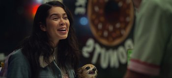 Movie still from “All Together Now” (2020), directed by Brett Haley – A woman smiling with a dog in front of a donut shop; Close Up shot, Over the shoulder angle