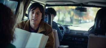 Movie still from “All Together Now” (2020), directed by Brett Haley – A person sitting in a car reading a book; Medium shot, Over the shoulder angle