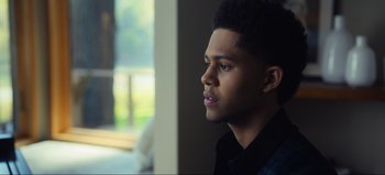 Movie still from “All Together Now” (2020), directed by Brett Haley – A young black man sitting in front of a window; Close Up shot, Over the shoulder angle