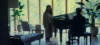 Movie still from “All Together Now” (2020), directed by Brett Haley – A woman standing in front of a grand piano in a room; Wide shot, Low angle