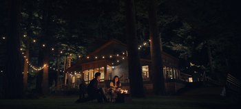 Movie still from “All Together Now” (2020), directed by Brett Haley – Two people sitting around a fire pit at night; Extreme Wide shot, High angle
