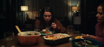 Movie still from “All Together Now” (2020), directed by Brett Haley – A woman sitting at a dinner table with a plate of food in front of her; Medium shot, High angle