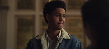Movie still from “All Together Now” (2020), directed by Brett Haley – A young man in a denim jacket looking to his left; Close Up shot, Over the shoulder angle