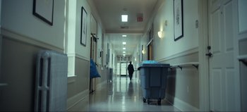 Movie still from “All Together Now” (2020), directed by Brett Haley – A person walking down a hallway with a trash can in it; Wide shot, Low angle