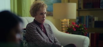 Movie still from “All Together Now” (2020), directed by Brett Haley – An older woman sitting on a couch in front of a lamp; Medium shot, Over the shoulder angle