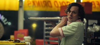 Movie still from “All Together Now” (2020), directed by Brett Haley – A man holding a tray of pizza in a restaurant; Medium shot, Low angle