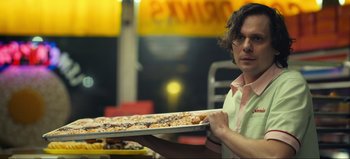 Movie still from “All Together Now” (2020), directed by Brett Haley – A man holding a tray of doughnuts in a restaurant; Medium shot, Low angle