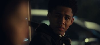 Movie still from “All Together Now” (2020), directed by Brett Haley – A young man in a hooded jacket looking at the camera; Close Up shot, Over the shoulder angle