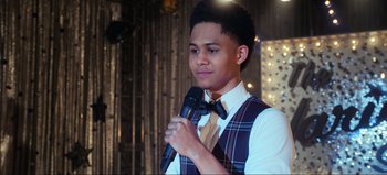 Movie still from “All Together Now” (2020), directed by Brett Haley – A young man holding a microphone in his hand; Close Up shot, Over the shoulder angle