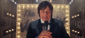 Movie still from “All Together Now” (2020), directed by Brett Haley – A man holding a microphone in front of a crowd; Close Up shot, Over the shoulder angle