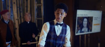 Movie still from “All Together Now” (2020), directed by Brett Haley – A man in a vest and bow tie standing in a room; Medium shot, Over the shoulder angle