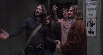 Movie still from “Almost Famous” (2000), directed by Cameron Crowe – A group of people standing around each other in a room; Medium shot, Low angle