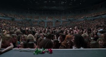 Movie still from “Almost Famous” (2000), directed by Cameron Crowe – A crowd of people in an arena with a rose in the foreground; Extreme Wide shot, High angle
