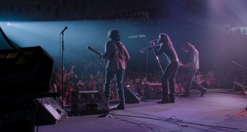 Movie still from “Almost Famous” (2000), directed by Cameron Crowe – Two people on a stage singing into microphones in front of an audience; Wide shot, Low angle