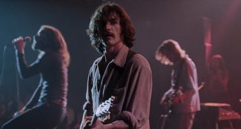 Movie still from “Almost Famous” (2000), directed by Cameron Crowe – A man holding a guitar while standing next to another man; Medium shot, Low angle