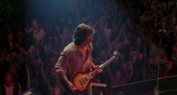 Movie still from “Almost Famous” (2000), directed by Cameron Crowe – A man playing a guitar in front of an audience; Medium shot, High angle