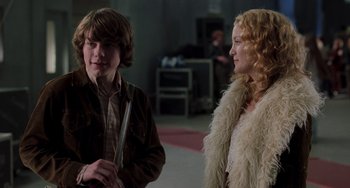 Movie still from “Almost Famous” (2000), directed by Cameron Crowe – A young man and a young woman standing next to each other; Medium shot, Over the shoulder angle