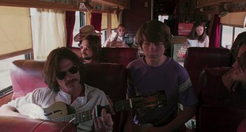Movie still from “Almost Famous” (2000), directed by Cameron Crowe – A group of people sitting on a bus playing guitar; Medium shot, Low angle