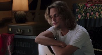 Movie still from “Almost Famous” (2000), directed by Cameron Crowe – A man with long brown hair is leaning on a guitar; Close Up shot, Low angle