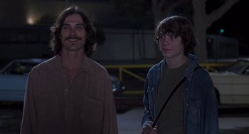 Movie still from “Almost Famous” (2000), directed by Cameron Crowe – A man standing next to a young boy; Medium shot, Low angle