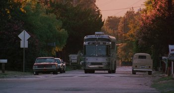 Movie still from “Almost Famous” (2000), directed by Cameron Crowe – A city bus driving down a street next to parked cars; Wide shot, Low angle