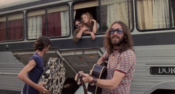 Movie still from “Almost Famous” (2000), directed by Cameron Crowe – A man holding a guitar standing in front of a bus; Medium shot, Low angle