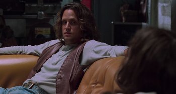 Movie still from “Almost Famous” (2000), directed by Cameron Crowe – A man sitting on top of a couch in a living room; Medium shot, Over the shoulder angle