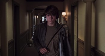 Movie still from “Almost Famous” (2000), directed by Cameron Crowe – A young man holding a bag while standing in a hallway; Medium shot, Low angle