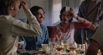 Movie still from “Almost Famous” (2000), directed by Cameron Crowe – A group of people sitting around a table with wine glasses; Medium shot, Over the shoulder angle