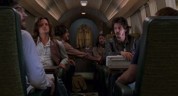 Movie still from “Almost Famous” (2000), directed by Cameron Crowe – A group of people sitting on a plane; Medium shot, Low angle