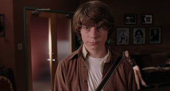 Movie still from “Almost Famous” (2000), directed by Cameron Crowe – A young man in a brown jacket holding a guitar strap; Close Up shot, Over the shoulder angle