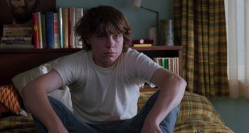Movie still from “Almost Famous” (2000), directed by Cameron Crowe – A young man sitting on a couch in front of a bookshelf; Medium shot, Low angle