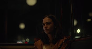 Movie still from “Along for the Ride” (2022), directed by Sofia Alvarez – A woman in a brown jacket is looking out a window at night; Close Up shot, Low angle