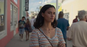 Movie still from “Along for the Ride” (2022), directed by Sofia Alvarez – A young woman is standing on the sidewalk; Close Up shot, Over the shoulder angle