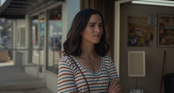 Movie still from “Along for the Ride” (2022), directed by Sofia Alvarez – A young woman standing in front of a store window; Close Up shot, Over the shoulder angle