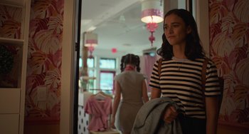 Movie still from “Along for the Ride” (2022), directed by Sofia Alvarez – A woman standing in front of a mirror holding a jacket; Medium shot, Over the shoulder angle