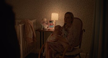 Movie still from “Along for the Ride” (2022), directed by Sofia Alvarez – A woman sitting in a rocking chair holding a baby; Medium shot, High angle